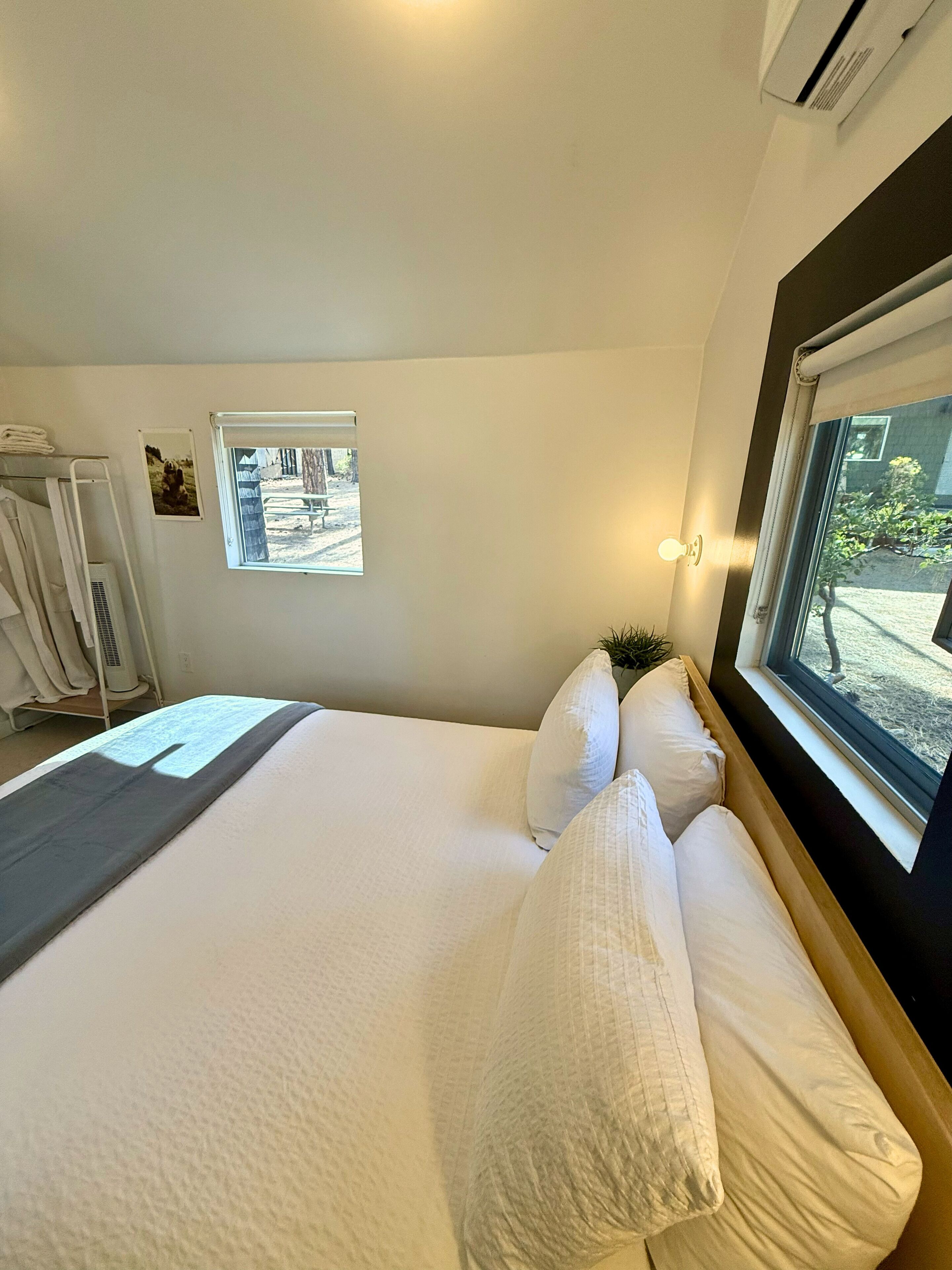 Un dormitorio con una cama grande, una ventana con vistas, aire acondicionado montado en la pared y un perchero para toallas.