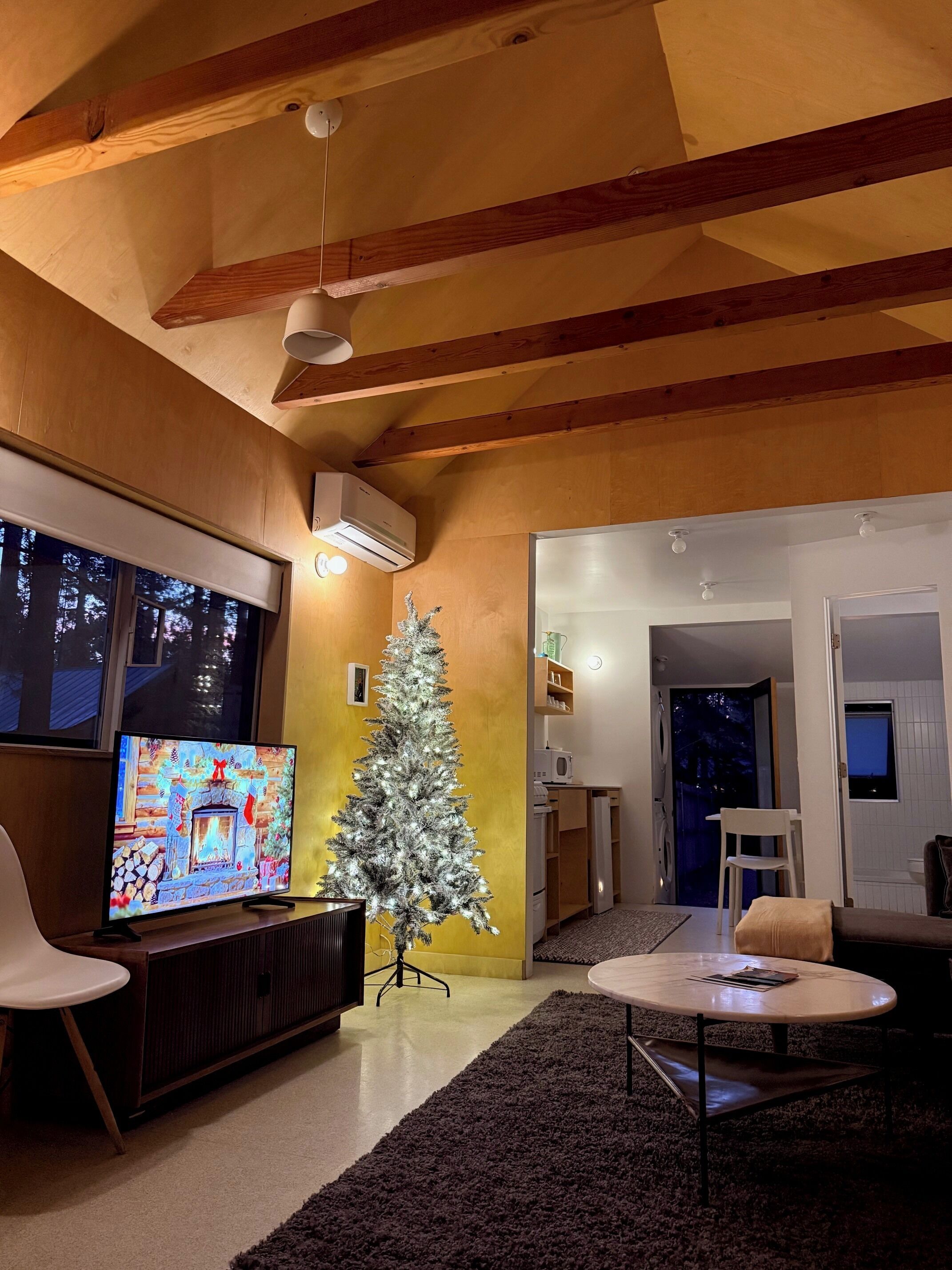 Ein Wohnzimmer mit Fernseher, Weihnachtsbaum und Kamin.