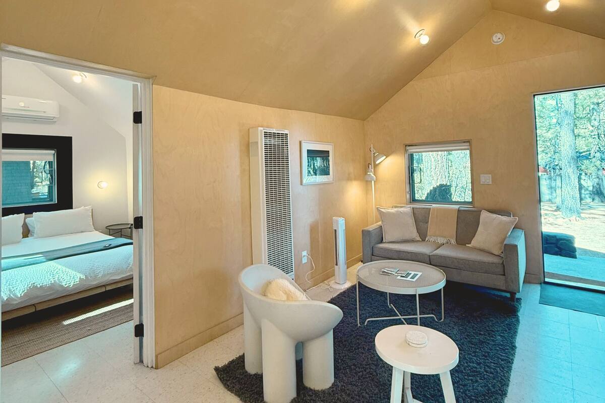 A modern interior with a bed, sofa, and a small round table.
