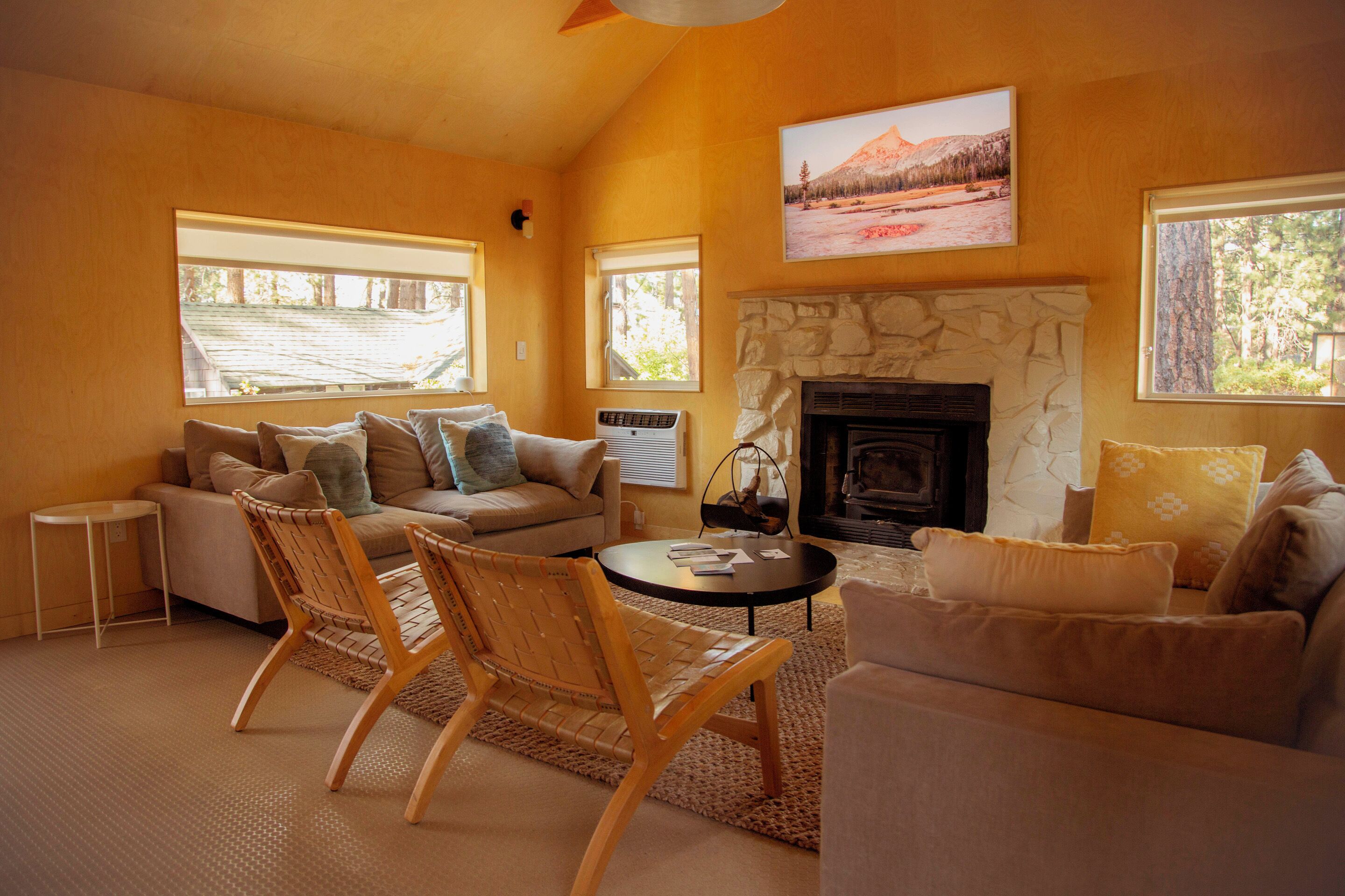 A cozy living room with a stone fireplace, a sofa, two armchairs, and a small table.