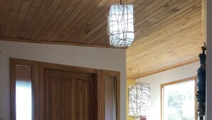 A wooden door with a frosted glass panel, a wooden staircase with a colorful cloth, and a hanging light fixture. - Hamilton's Place (Puerto Varas)