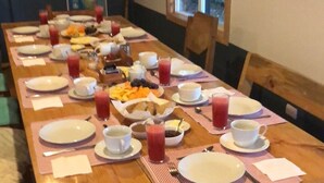 A wooden dining table set with plates, bowls, and glasses, likely for breakfast. - Hamilton's Place (Puerto Varas)