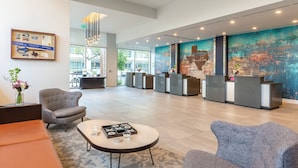 A spacious lobby with a reception desk, seating area, and a large abstract mural. - DOWNTOWN Austin with ROOFTOP Pool and BBQ Area, Fire Pit & a Fitness Center (Austin)
