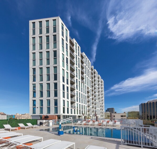 A modern high-rise hotel with a rooftop pool area, featuring sun loungers and a clear blue sky. - DOWNTOWN Austin with ROOFTOP Pool and BBQ Area, Fire Pit & a Fitness Center (Austin)