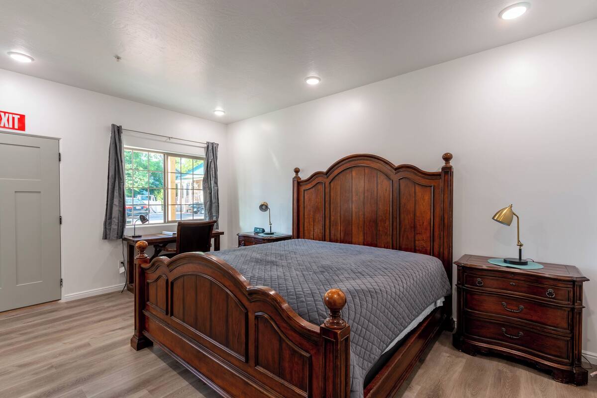 A bedroom with a wooden bed, a desk, and a dresser.