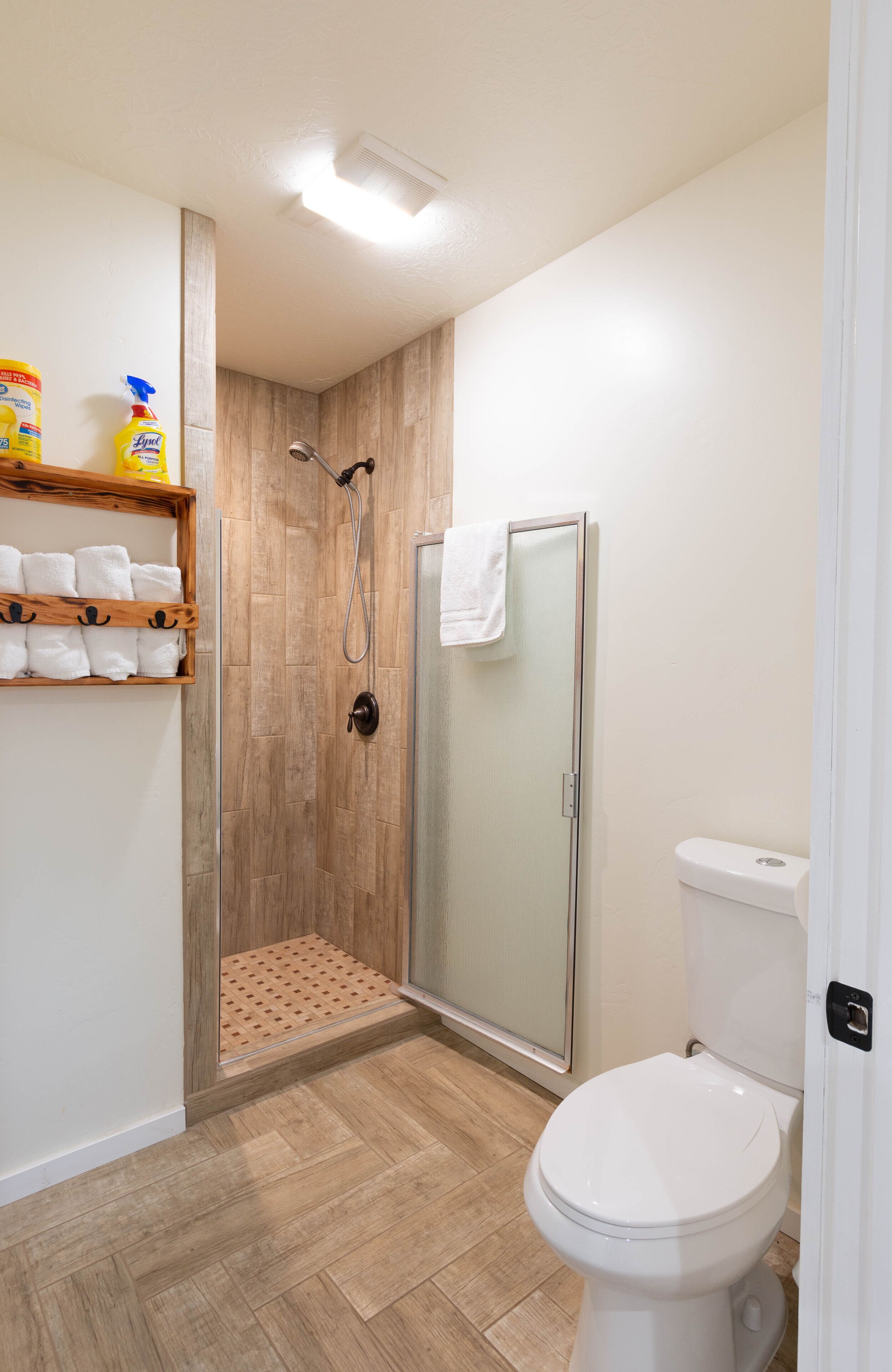 Une salle de bain avec une douche, des toilettes et une étagère avec des serviettes.
