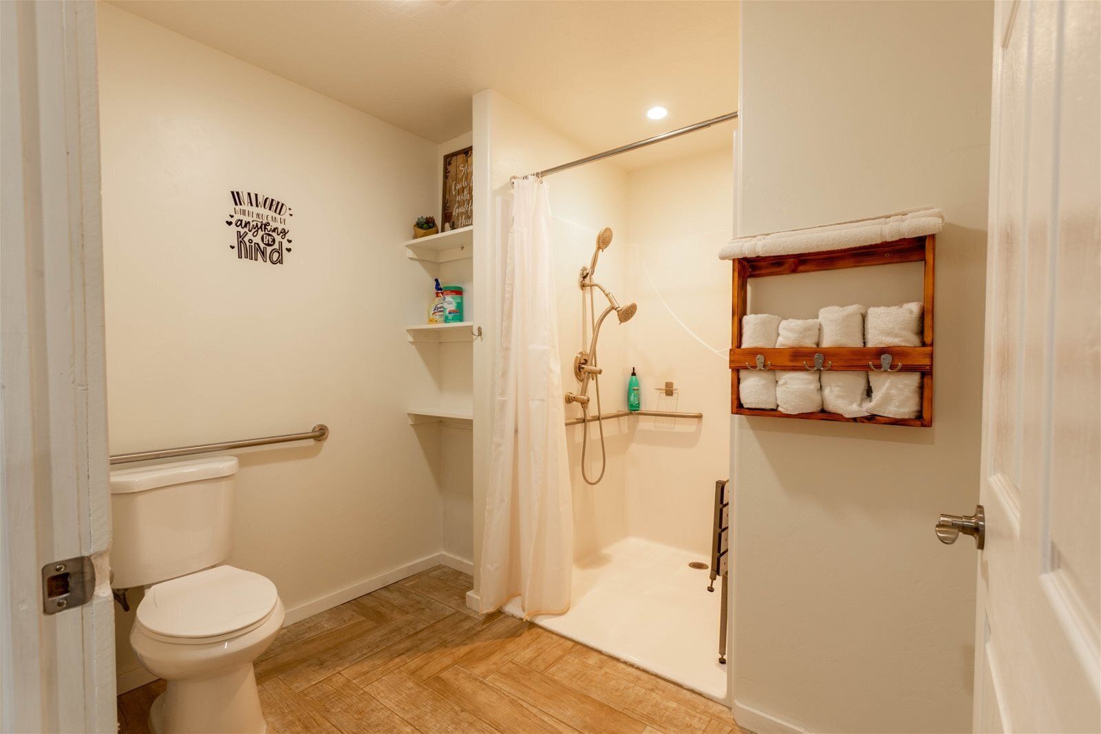A bathroom with a toilet, shower, and a shelf with towels.