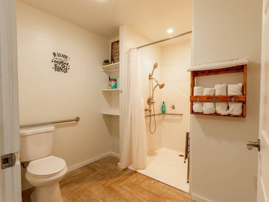 A bathroom with a toilet, shower, and a shelf with towels.