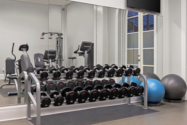 Un gimnasio con jaulas para pesas, equipo de ejercicio y pelotas de ejercicio.