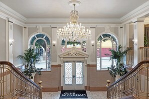 Un hall imponente con una araña, ventanas arqueadas y un felpudo que dice 'CLUB WYNDHAM'.