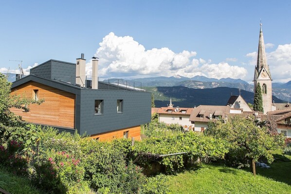 A modern house with a sloped roof, a wooden exterior, and a small window.