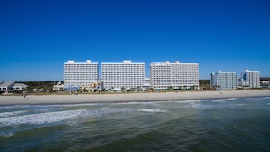 A beachfront hotel with multiple high-rise buildings, a sandy beach, and ocean waves. - Wonderful Oceanfront Efficiency w/ Great View+Official On-Site Rental Privileges (Myrtle Beach)