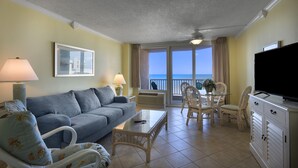 A living room with a sofa, chairs, a table, a TV, and a balcony with a view of the sea. - Angle Oceanfront King Suite at Fun Resort + Official On-Site Rental Privileges (Myrtle Beach)