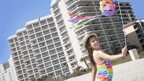 A person holding a kite on a beach with high-rise buildings in the background. - Angle Oceanfront King Suite at Fun Resort + Official On-Site Rental Privileges (Myrtle Beach)