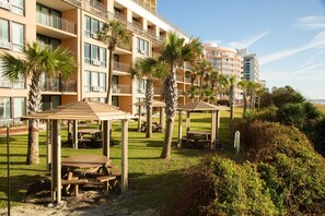 Un patio de hotel con mobiliario exterior, palmeras y vistas a los balcones del edificio.