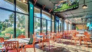 Un restaurant spacieux avec de grandes fenêtres, des chaises orange et une table centrale.