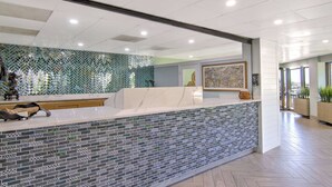 A reception area with a marble counter, mosaic tile wall, and framed artwork.