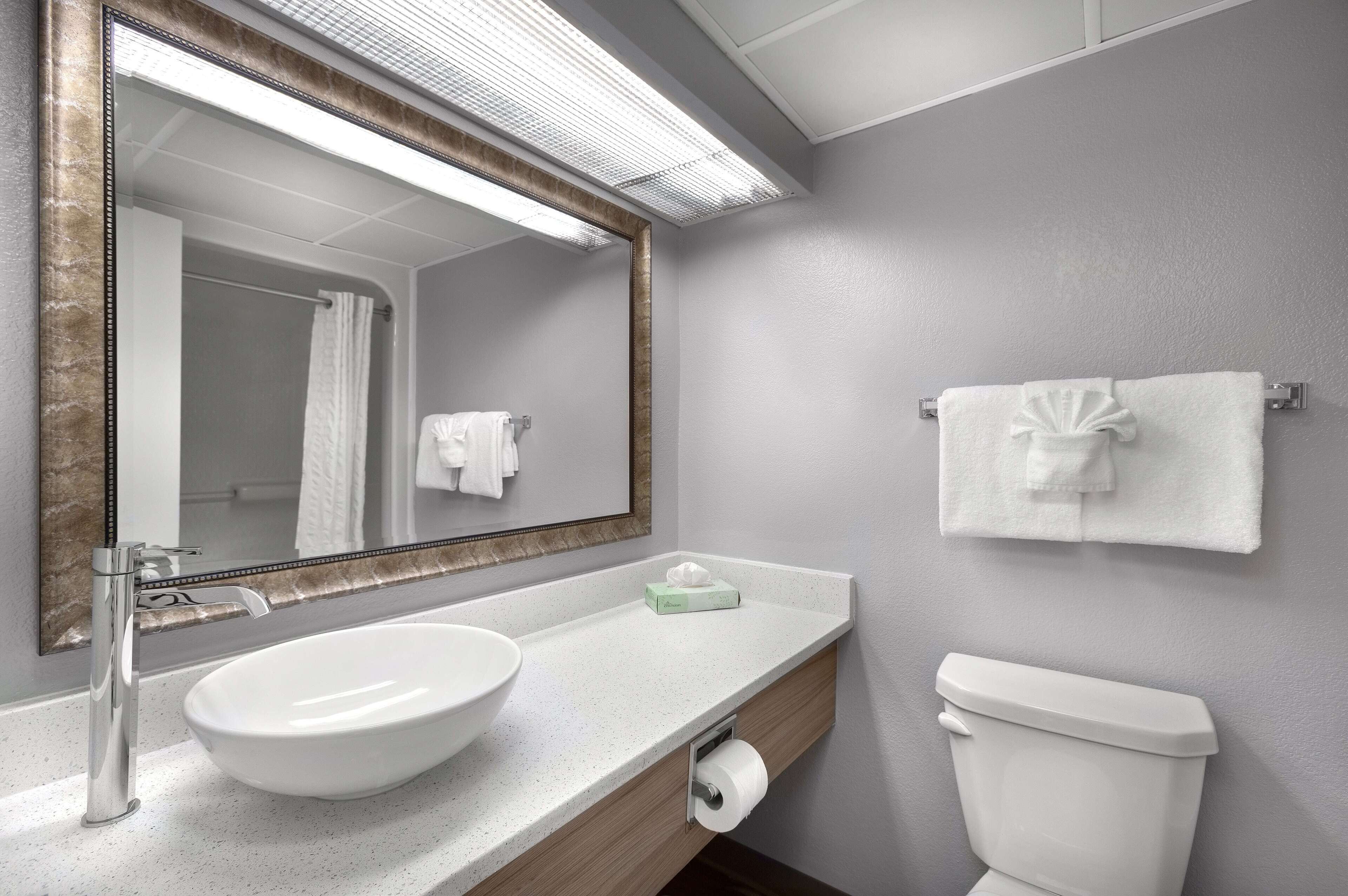 A bathroom with a white sink, a mirror, a towel rack, and a toilet.