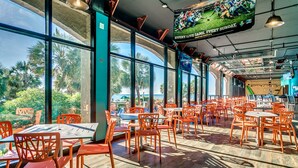 Un restaurant spacieux avec de grandes fenêtres, des chaises orange et une table centrale.