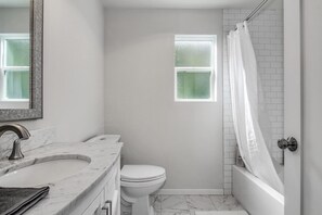 Ein Badezimmer mit Marmorwaschtisch, Toilette und Badewanne.