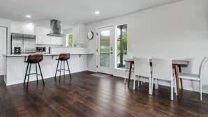 A modern kitchen with white cabinets, stainless steel appliances, and a bar area with stools. - Downtown Kirkland - Luxury 3rd Street Retreat (Kirkland)