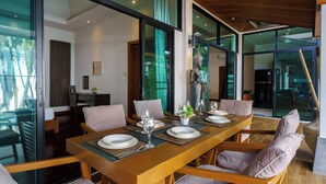 A modern dining area with a wooden table set for six, surrounded by cushioned chairs. - Emotion2 - Brand New 3BR Pool Villa (Tambon Rawai)