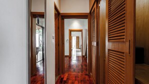 A hallway with wooden flooring and doors, leading to a room with a bed. - Emotion2 - Brand New 3BR Pool Villa (Tambon Rawai)