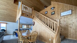 A wooden interior with a dining area, kitchen, and a staircase.