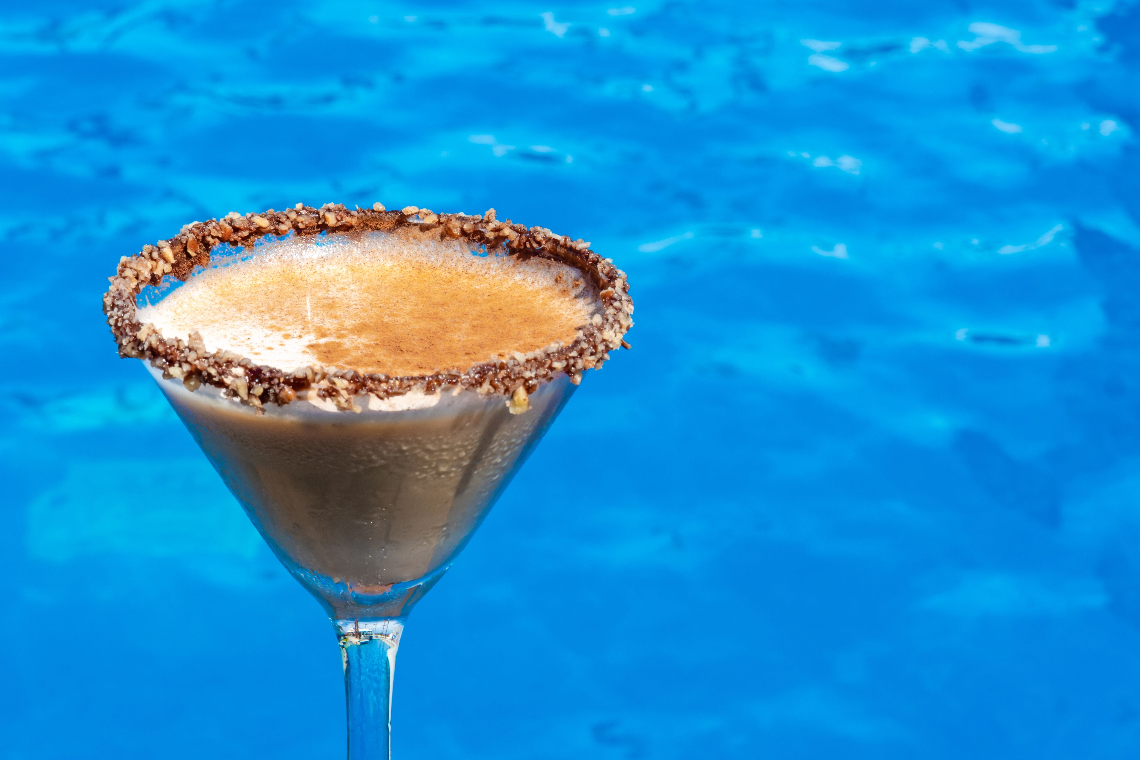 Una copa de martini con borde salado, sobre un fondo azul.