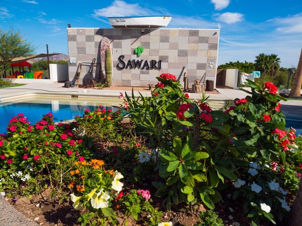 A pool area with a sign reading "SAWARI" and a boat named "San Carlos" on a dock. - Sawari Hotel (San Carlos)