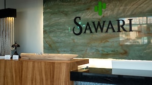 A reception desk with a marble wall behind it, displaying the name "SAWARI". - Sawari Hotel (San Carlos)