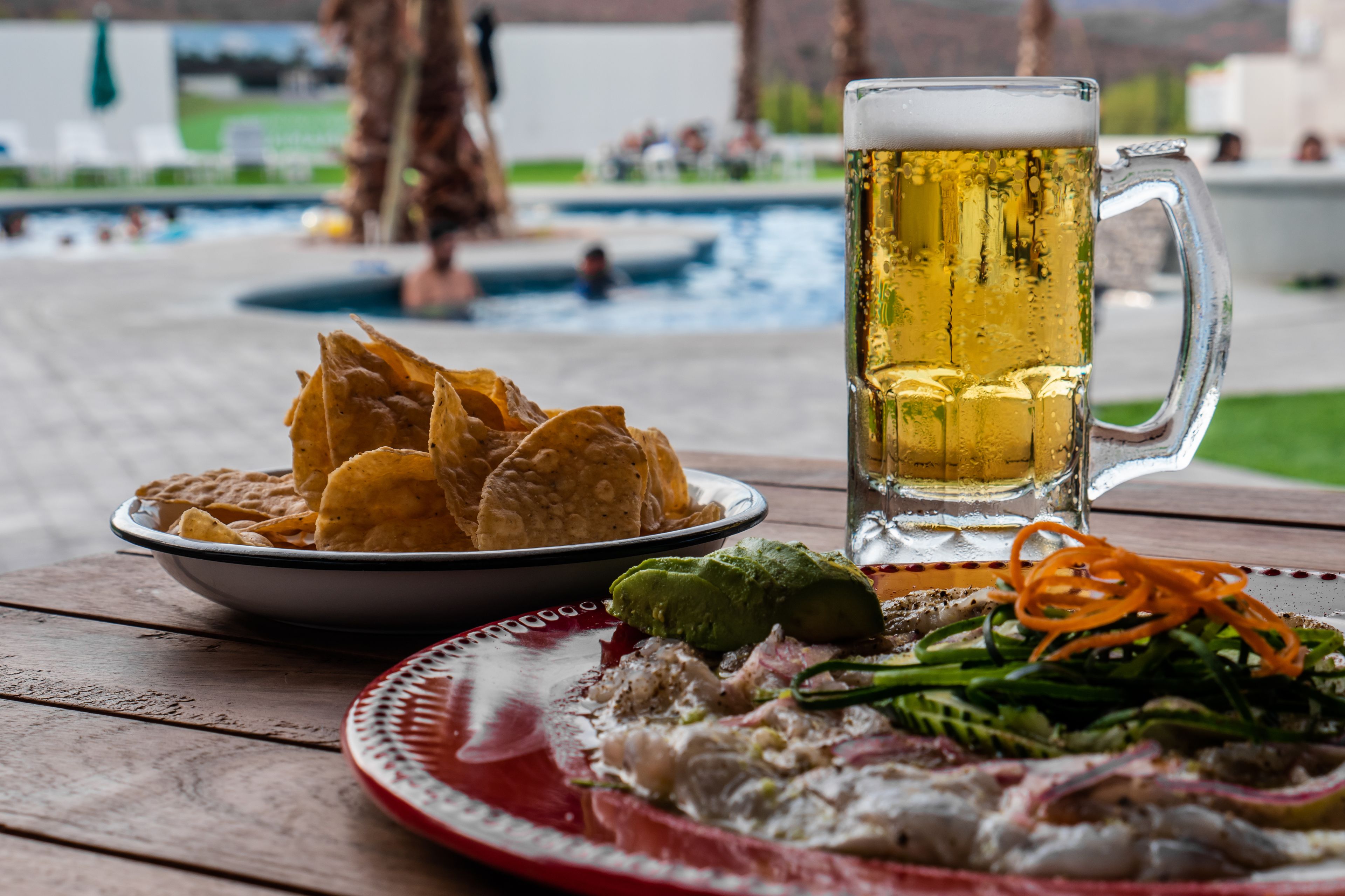 Une table avec une assiette de frites, un bol de guacamole, une assiette de ceviche et une chope de bière.