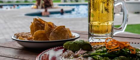 Une table avec une assiette de frites, un bol de guacamole, une assiette de ceviche et une chope de bière.