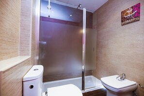 Ett modernt badrum med en dusch som är avskärmad med glasväggar, en toalett och ett handfat.
