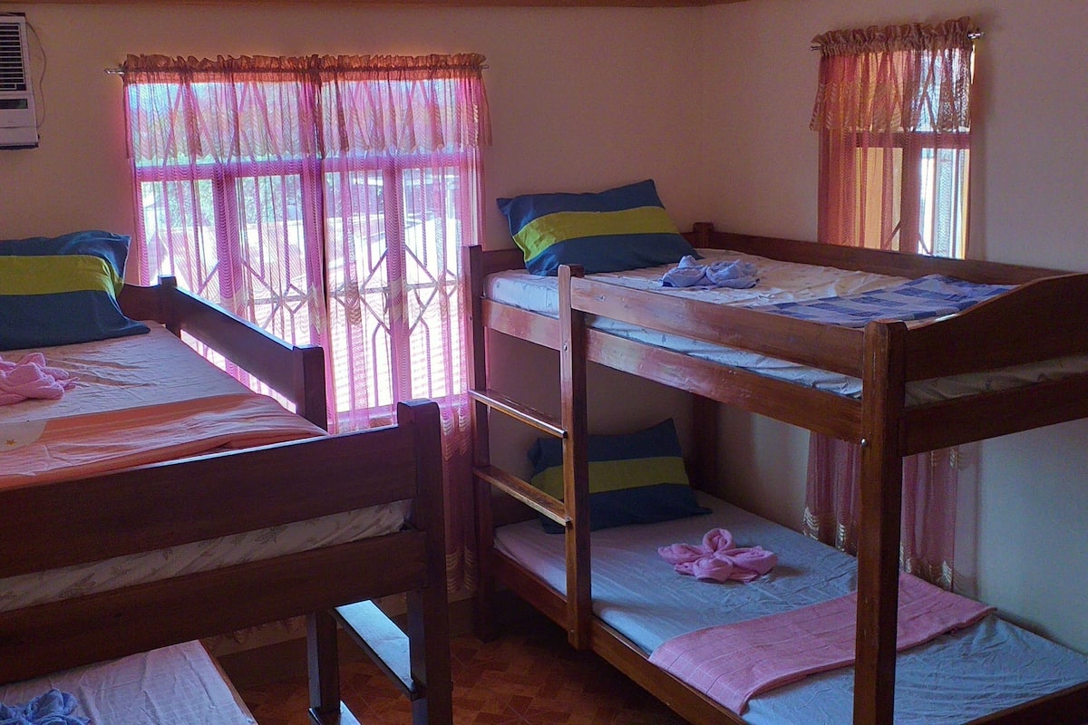 A room with two bunk beds, a window with curtains, and an air conditioning unit on the wall.