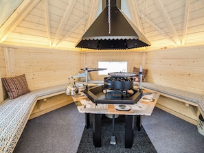 A cozy interior with a central table, a stove, and seating areas.