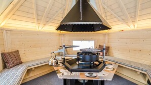 A cozy cabin interior with a central table, seating area, and a ceiling light fixture. - Welhotar by Interhome (Lieksa)