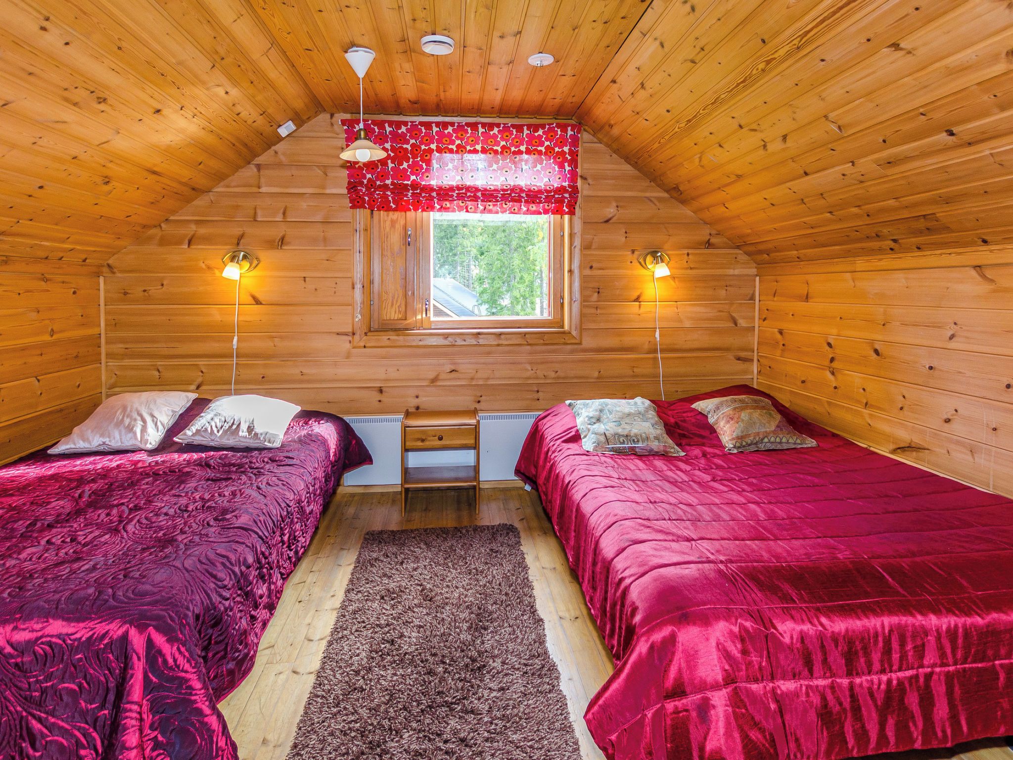 Una habitación acogedora tipo cabaña con dos camas, una ventana y un ventilador de techo.