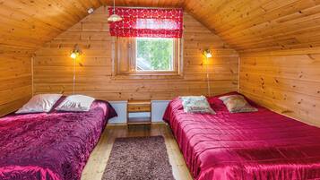 Una habitación acogedora tipo cabaña con dos camas, una ventana y un ventilador de techo.