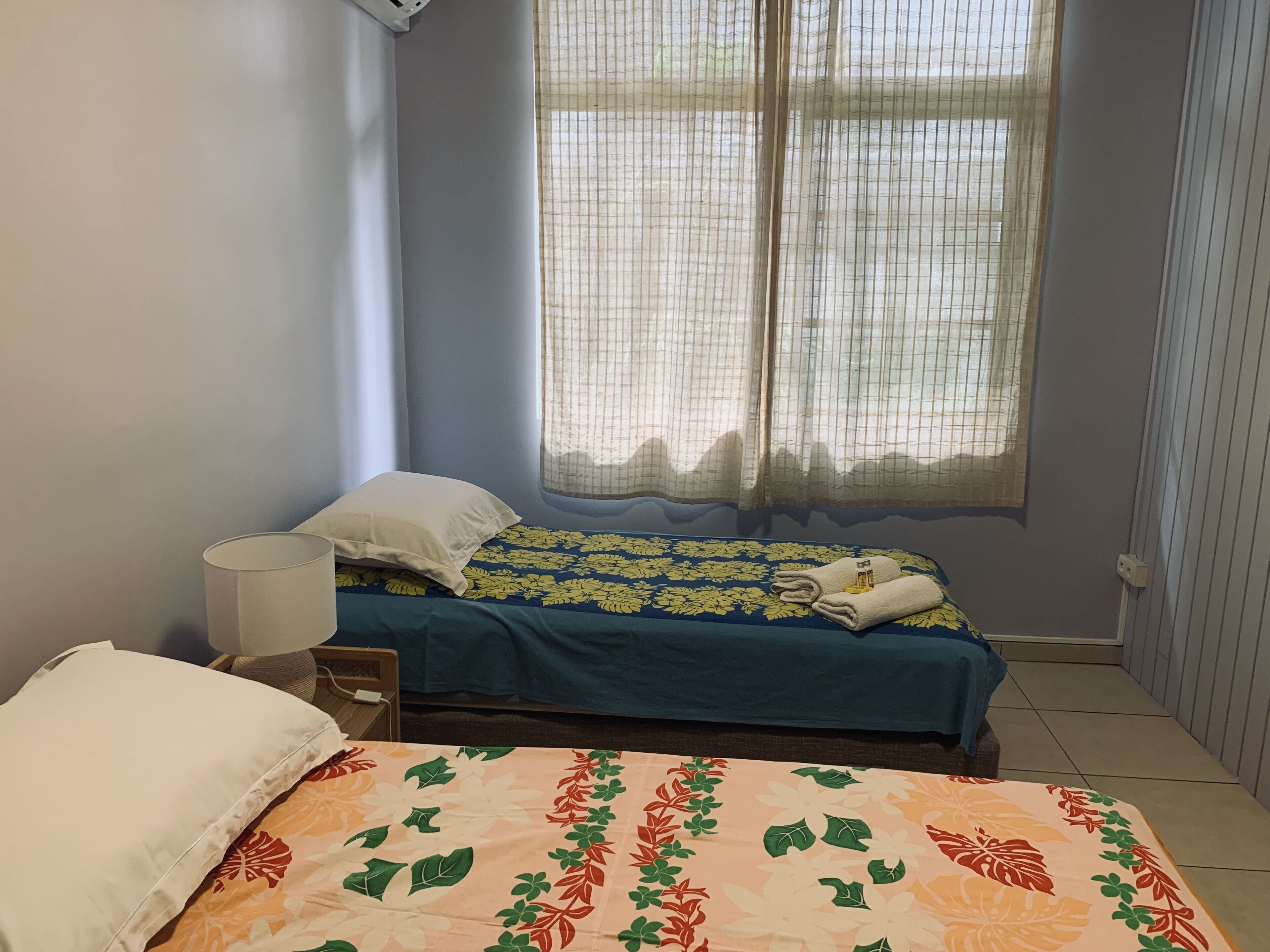 A bedroom with a bed, a bedside table, a lamp, and a window with curtains.