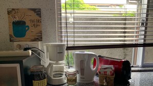 A kitchen counter with a coffee maker, sugar container, and a coffee jar. - City Home Tahiti (Papeete)