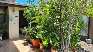 A courtyard with potted plants, a welcome sign, and a door to a building. - City Home Tahiti (Papeete)