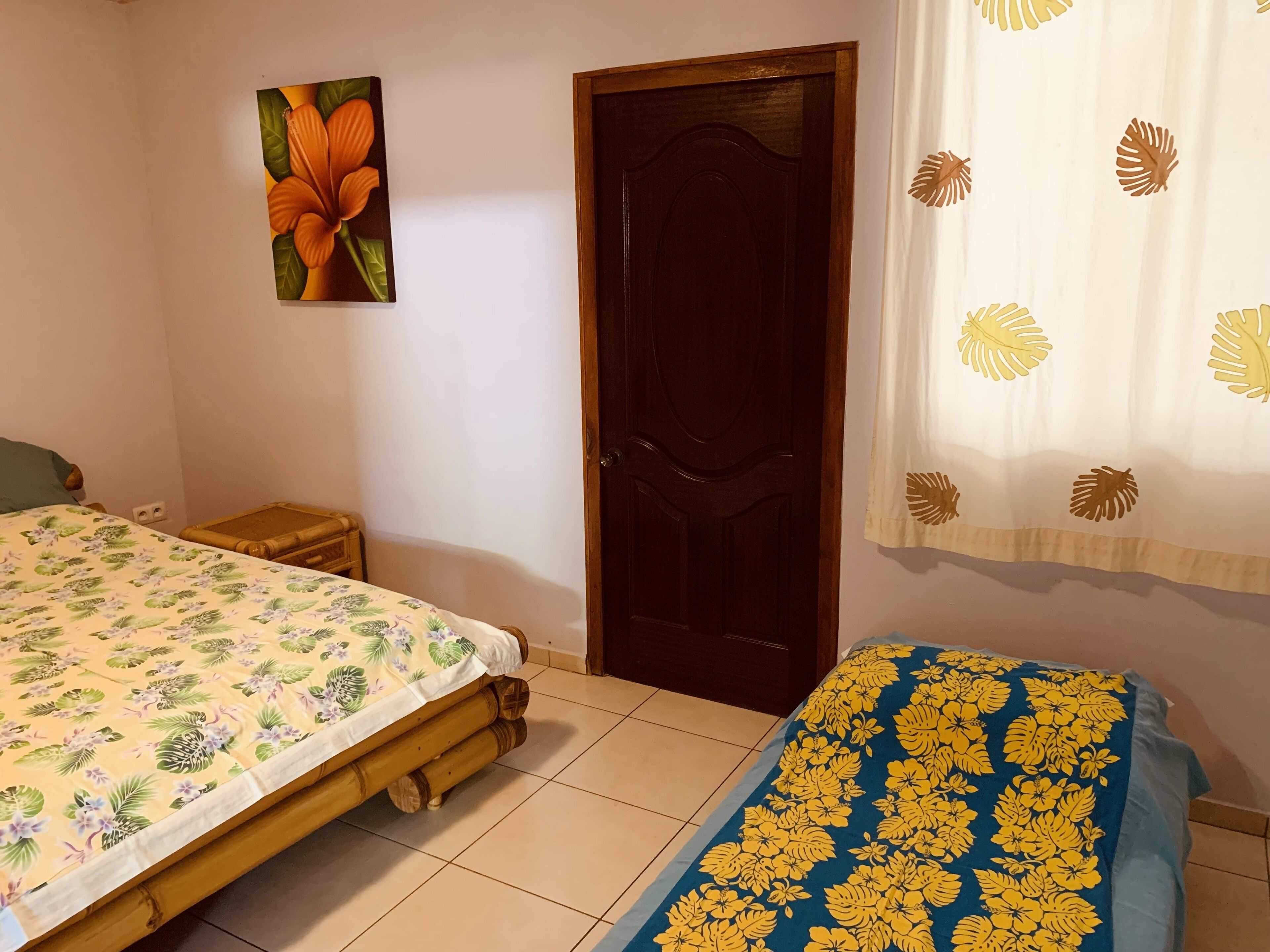 Ein Schlafzimmer mit Bett, Nachttisch, Holztür und einem an der Wand hängenden Gemälde.