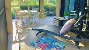Un patio luminoso con una poltrona prendisole, un tavolo rotondo e sedie.