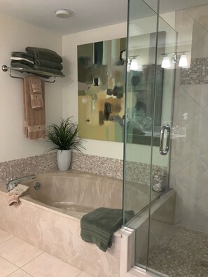 Een bad/douchecombinatie, een bubbelbad, een haardroger, handdoeken