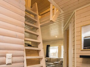 Un intérieur en bois avec un escalier central en bois, un canapé et un téléviseur fixé au mur.