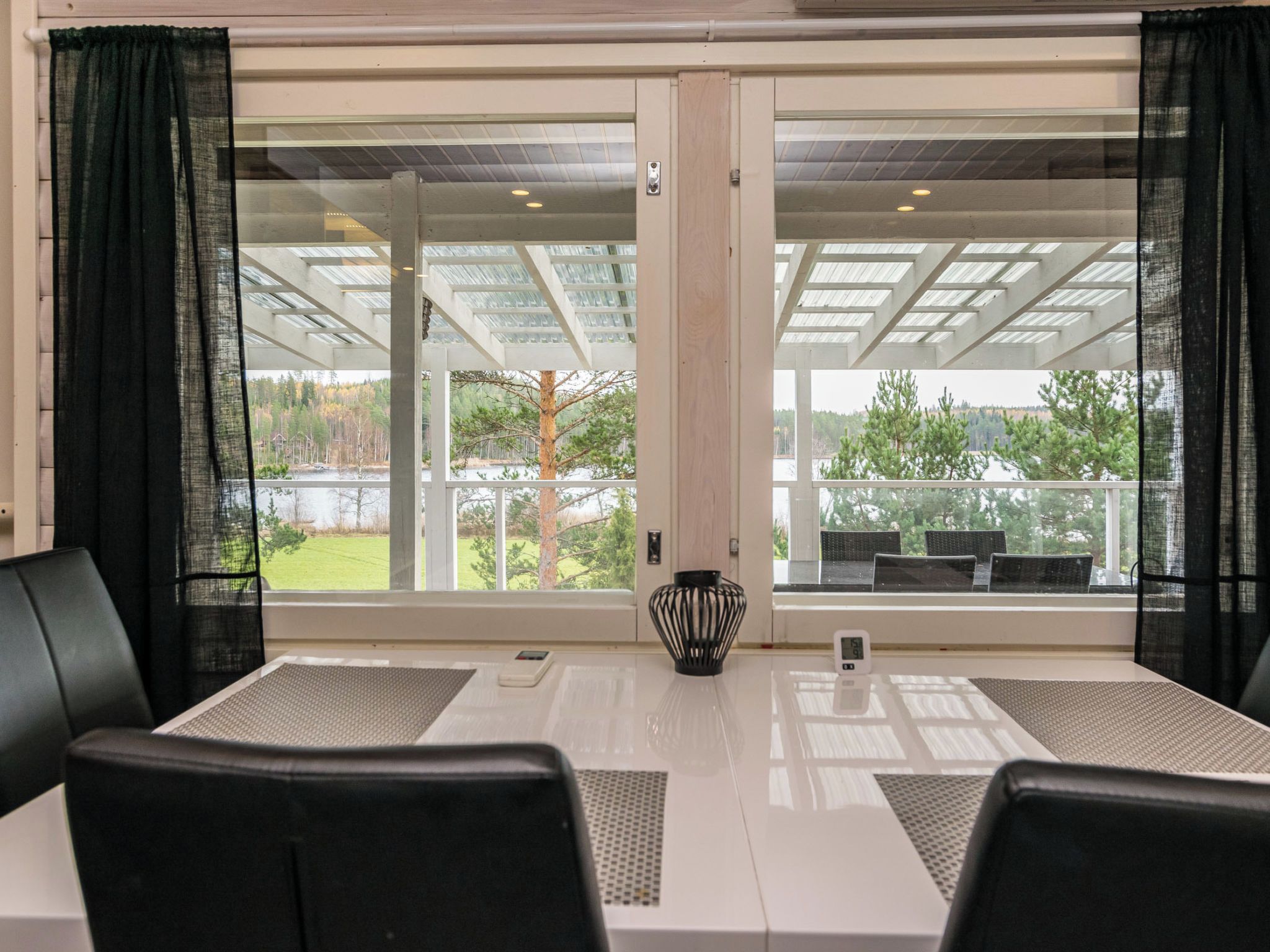 A conference room with a table, chairs, a vase, and a view of a balcony with outdoor seating.