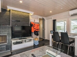 Un salon moderne doté d’un téléviseur à écran plat, d’une cheminée, d’un coin repas avec une table et des chaises, et offrant une vue sur l’extérieur grâce à une grande fenêtre.