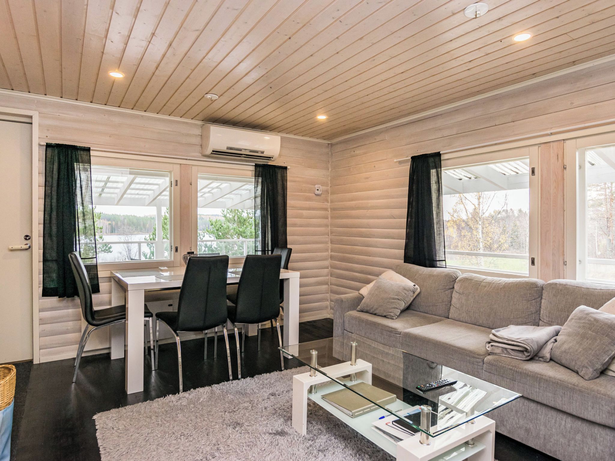 A modern living room with a sofa, a glass coffee table, and a dining area with chairs and a table.