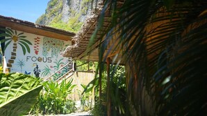 A building with a mural featuring tropical plants and the word "FOCUS". - Focus Rooms (El Nido)